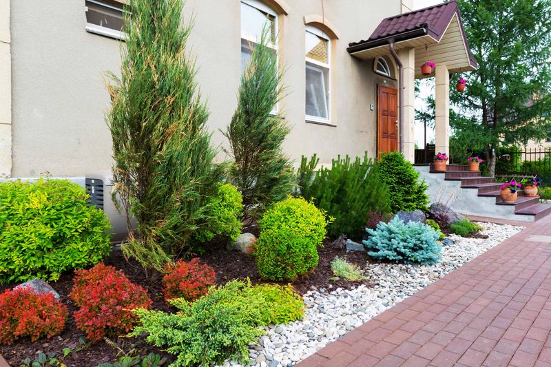 Freshly dressed stone mulch and clipped green shrubs beside the brick paver walkway into a commercial building's entrance